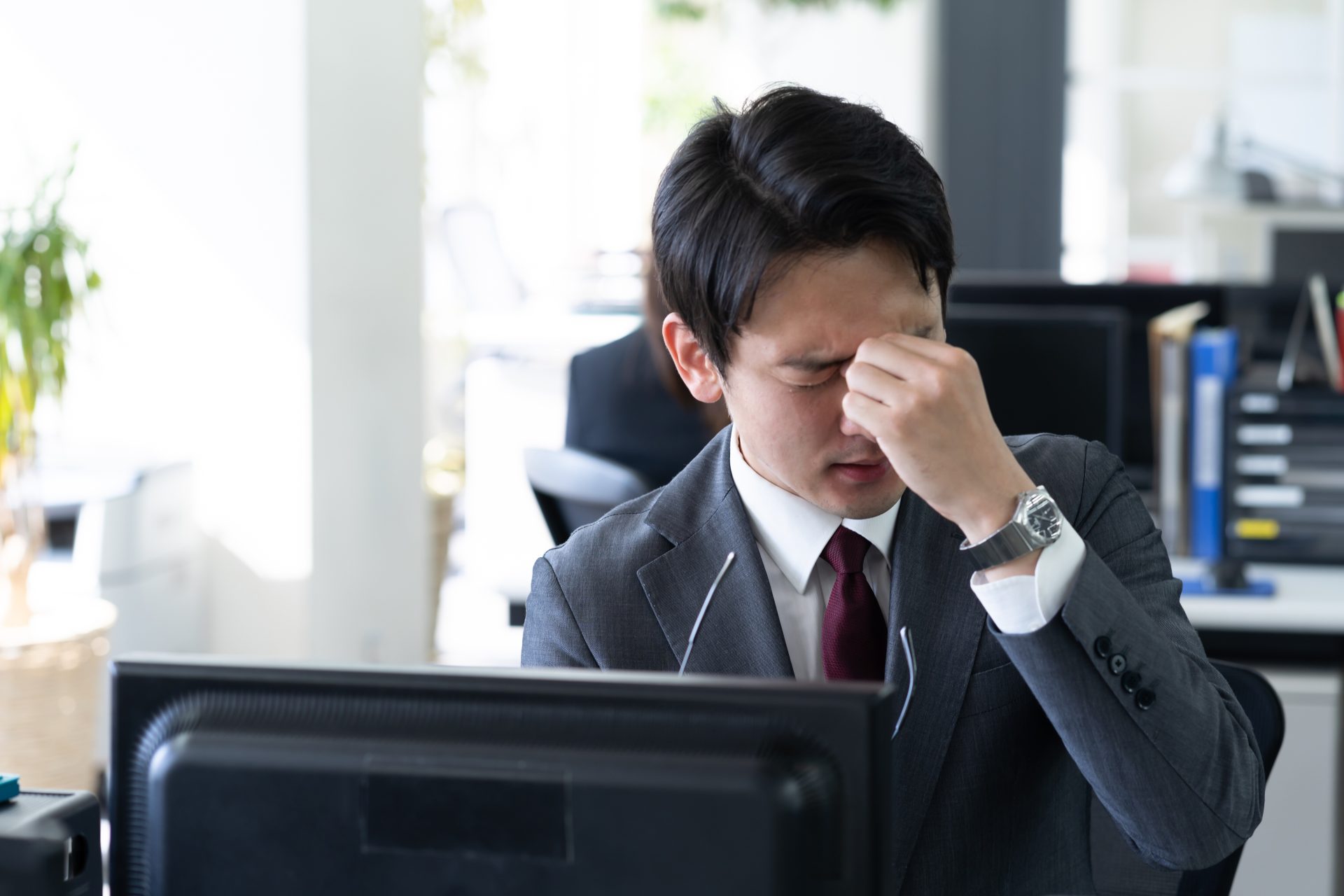 めまいで目を抑える男性